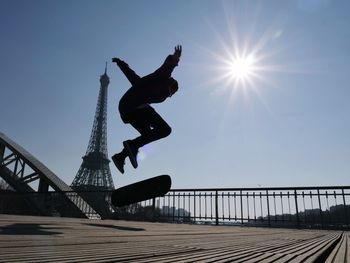 Low angle view of silhouette man skateboarding against eiffel tower