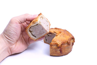 Close-up of hand holding bread against white background