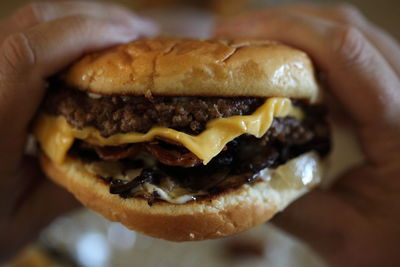 Close-up of cheeseburger in hands