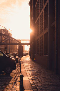 Street amidst buildings against sky during sunset