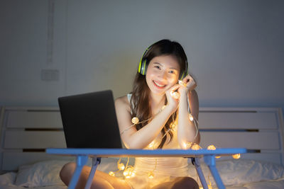 Portrait of young woman using phone while sitting on table