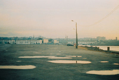 Road by buildings against sky in city