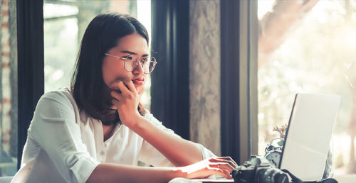 Young woman using mobile phone while sitting on table