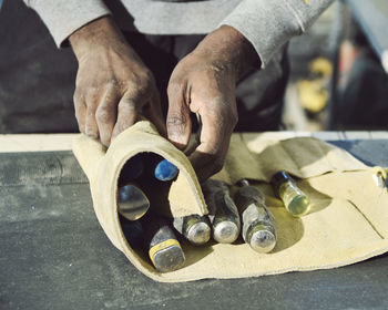 Midsection of carpenter holding work tools at workshop