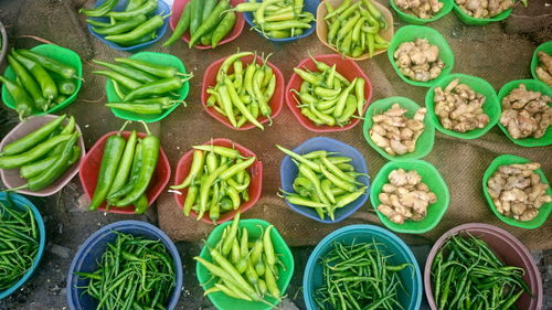 High angle view of green chili peppers in containers at market for sale
