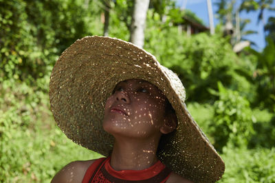 Portrait of an asian woman wearing a big straw hat in bright sunshine