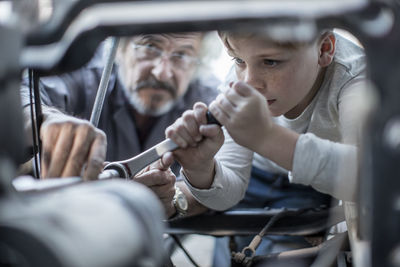 Senior man and boy working on mechanism of a car