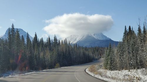 Panoramic view of road by snowcapped mountains against sky