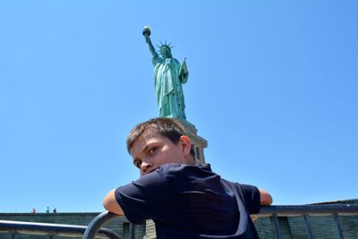 Low angle portrait of boy wearing blue against clear sky