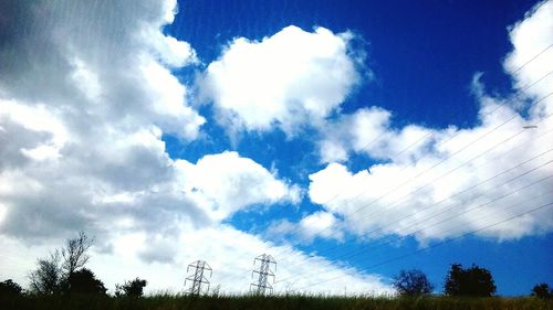 Low angle view of trees against cloudy sky