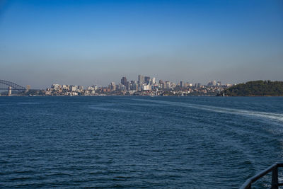 Sea by buildings against blue sky