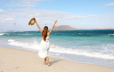 Rear view of woman at beach against sky