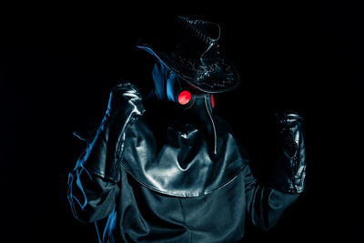 Midsection of woman wearing hat standing against black background