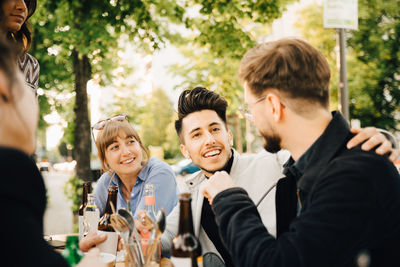 Smiling man sitting by male and female friend at social gathering