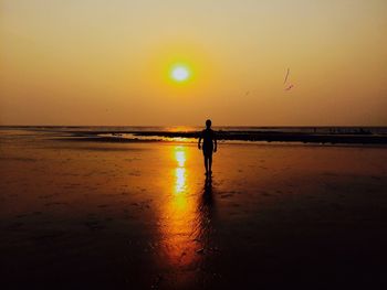 Silhouette man standing at beach against sky during sunset