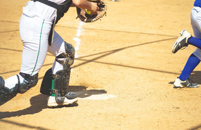 Low section of man playing baseball on field