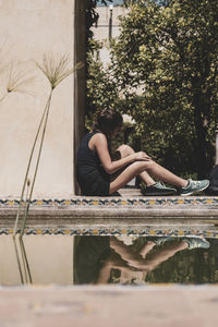 People sitting by plants against trees