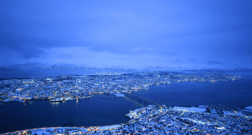 High angle view of buildings by sea against blue sky