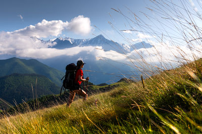Rear view of man walking on mountain against sky