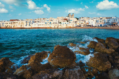 Scenic view of sea by buildings against sky