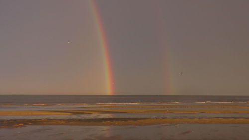 Scenic view of rainbow over sea against sky