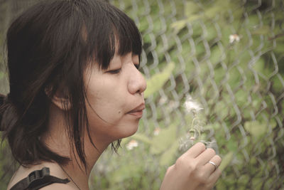 Close-up of woman blowing dandelion seed