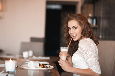 Portrait of young woman drinking coffee at restaurant
