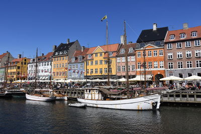 Sailboats moored on canal by buildings against sky in city