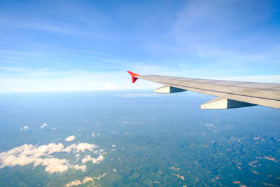 Airplane flying over landscape against blue sky