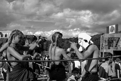 People in front of amusement park against cloudy sky