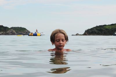 Shirtless boy swimming in sea