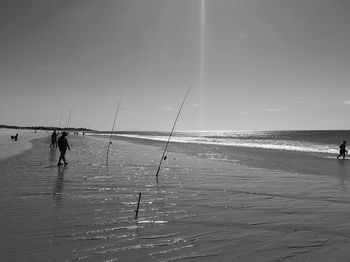 People fishing in sea against sky