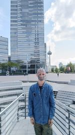 Portrait of young man standing against buildings