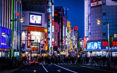 People on street amidst illuminated buildings in city