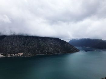 Scenic view of sea by mountain against sky