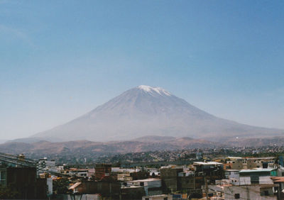 Town by mountains against clear blue sky