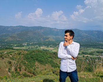 Young man standing on mountain against sky