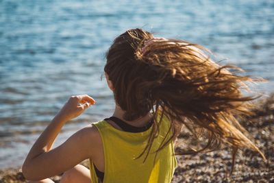 Rear view of woman with tousled hair against sea