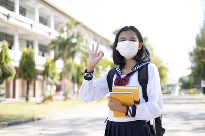 Portrait of girl wearing mask standing outdoors
