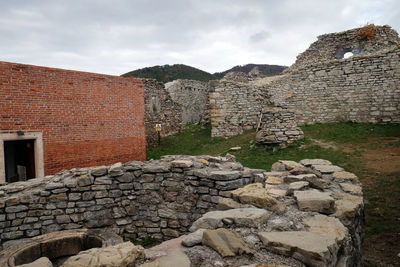 Stone wall of old building against cloudy sky