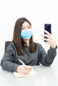 Portrait of young woman using smart phone against white background