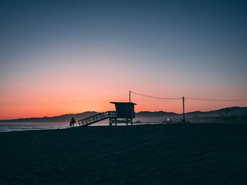 Silhouette beach by sea against sky during sunset