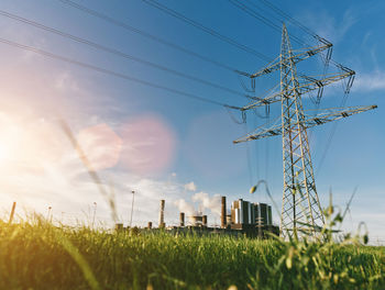 Low angle view of electricity pylon on field against sky