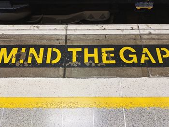 High angle view of yellow sign on train platform, mind the gap