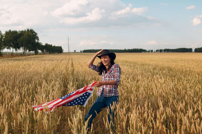 Rear view of woman standing on field against sky