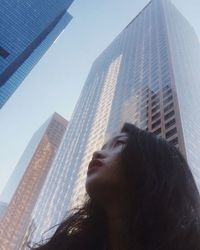 Low angle view of woman looking at modern building against sky