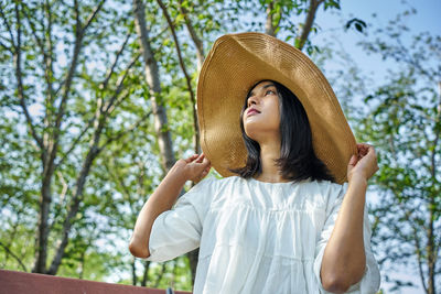 Full length of woman wearing hat standing against trees