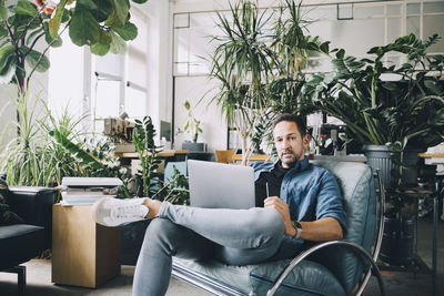 Young man using mobile phone while sitting on chair