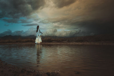 Rear view of woman standing against sky during sunset