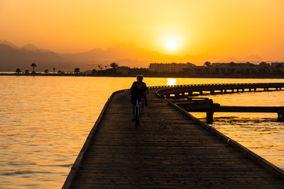 Front view of silhouette woman on pier against sky during sunset